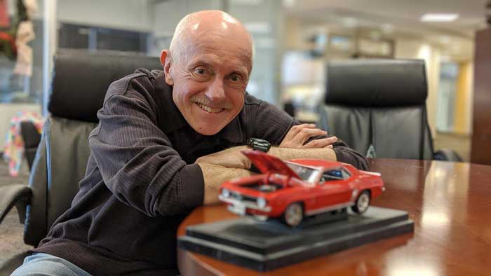 Car expert Joe Semens smiles beside a model car.